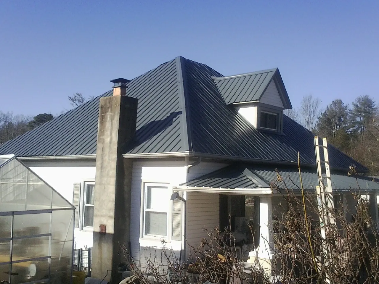 Dark blue standing seam metal roof on a white farmhouse with dormer — Slate & Tile Roof Repair by Roofing Brothers in Surgoinsville