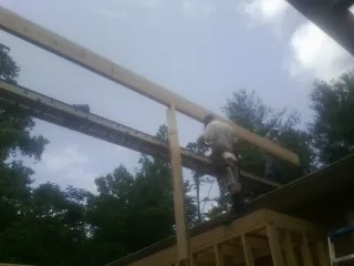 Carpenter setting a ridge beam over a new addition frame — Ice Dam Removal by Roofing Brothers in Surgoinsville