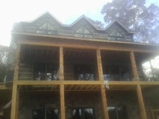 Dormers and porch framing on a large log home under construction — Roof Coating work by our crew in Surgoinsville