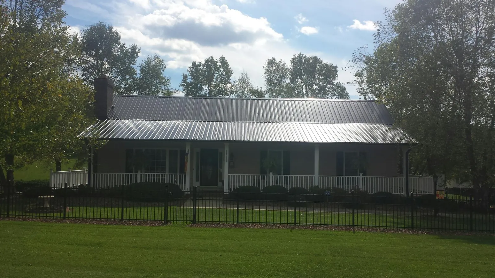 Gray metal roof on a brick ranch with a full width front porch — Gutter Guard Installation work by our crew in Surgoinsville