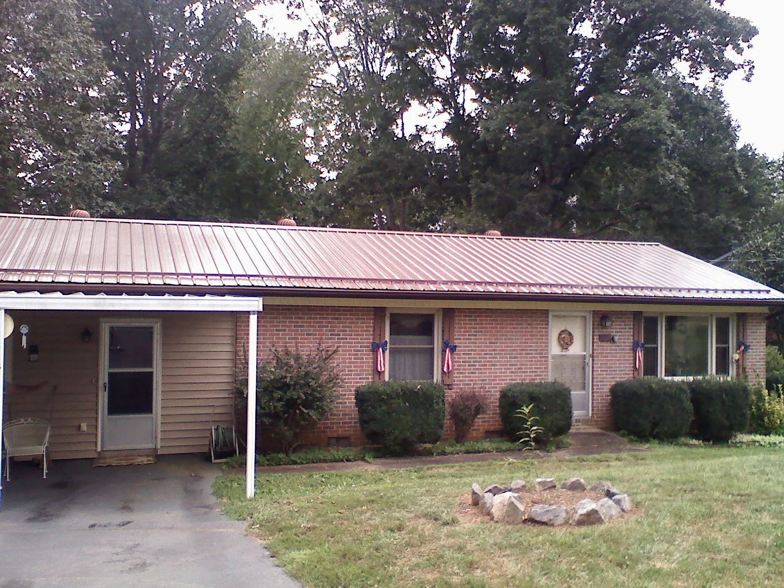 Bronze metal roof and carport on a brick ranch home — Roof Repair work by our crew in Surgoinsville