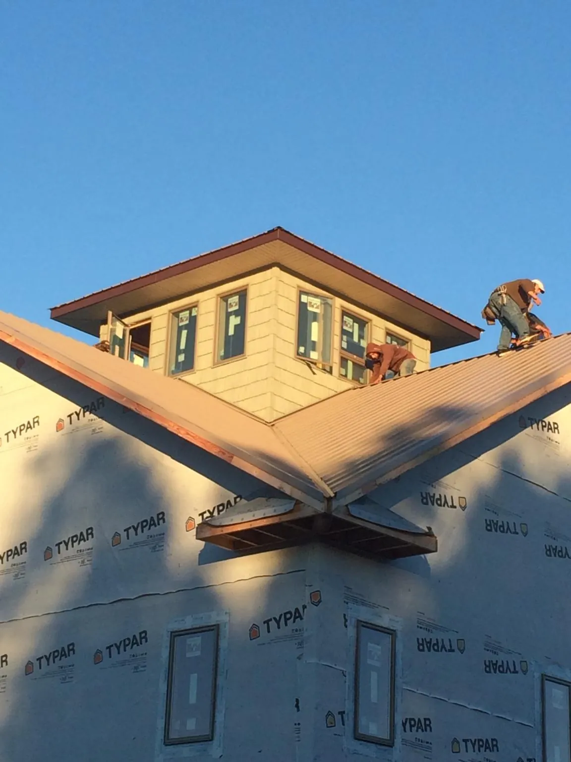 Roofers working around a rooftop cupola on a new metal roof at sunset — Roof Waterproofing in Surgoinsville by Roofing Brothers